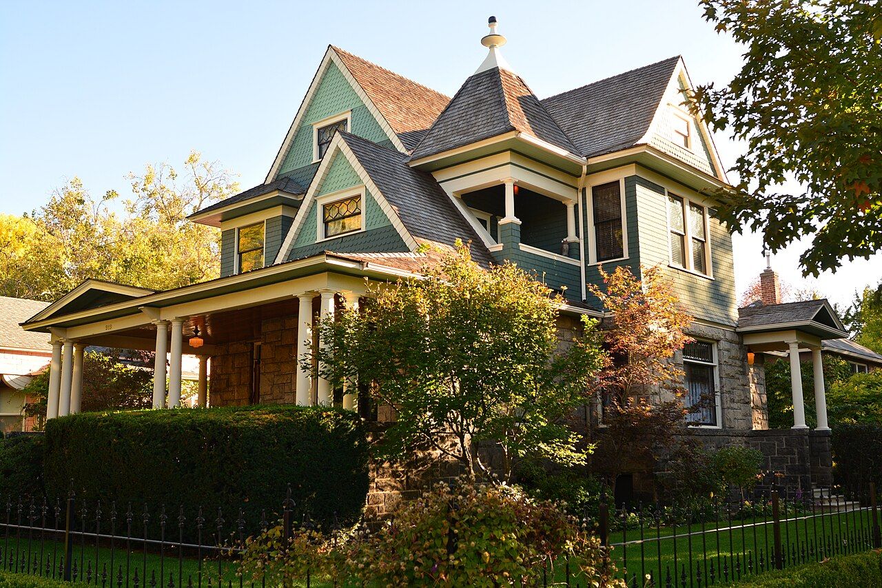 A green Victorian house with a wide porch and autumn trees in Boise's Fort Street Historic District